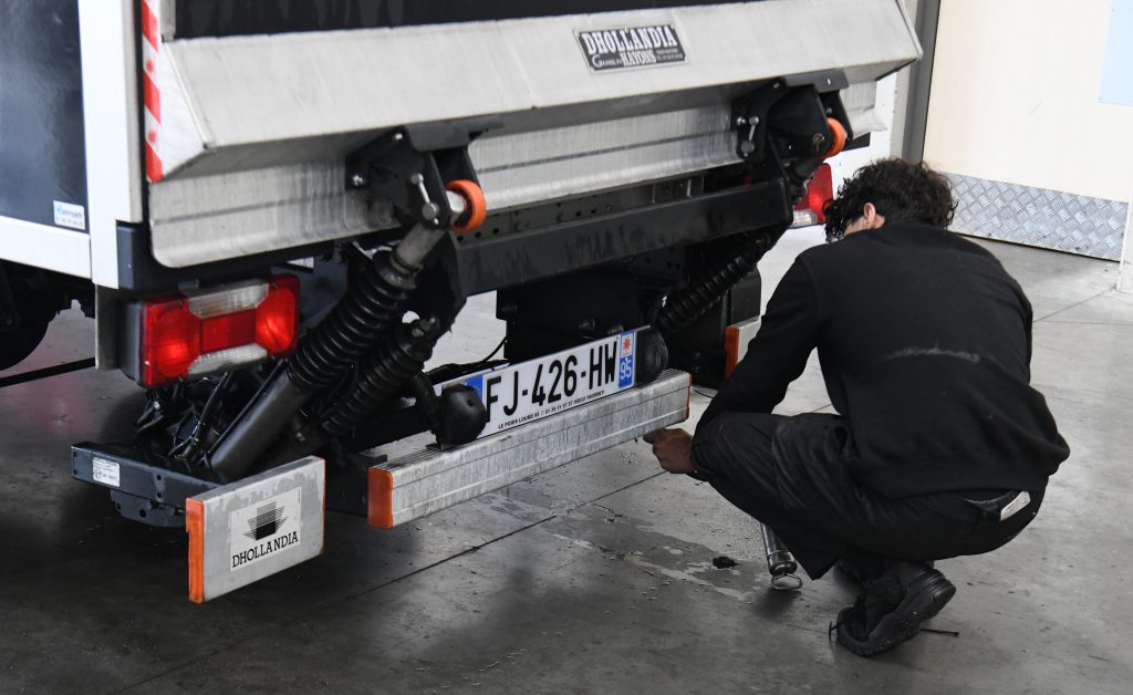 Technicien Dhollandia Services accroupi sous un hayon élévateur pour une réparation