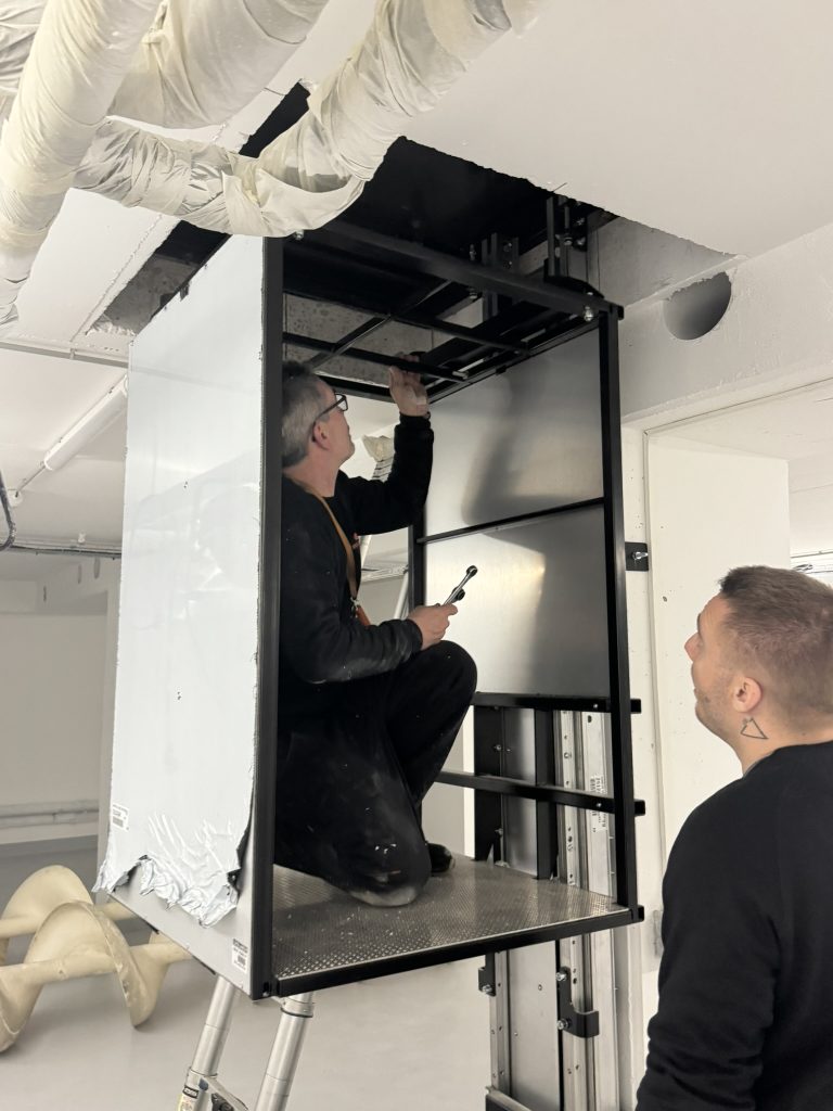 Technicien Dhollandia Services réglant un monte-charge dans une gaine